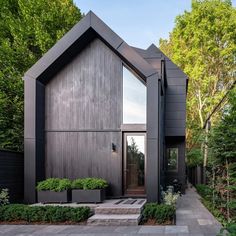 a modern house in the woods with steps leading up to it's front door