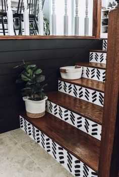 the stairs are decorated with black and white geometric tiles, potted plants on each step