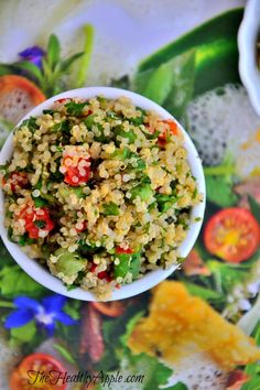 a bowl filled with rice and vegetables on top of a floral table cloth next to two bowls