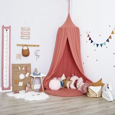 a bedroom with a pink canopy bed and pillows on the floor