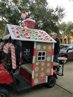 a man standing next to a small house made out of candy canes and gingerbread