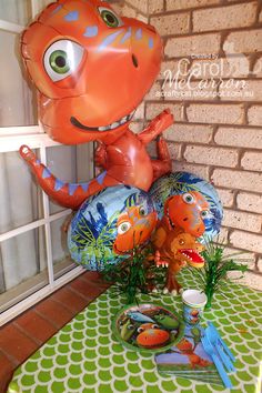 an inflatable dinosaur balloon sitting on top of a table next to some plants