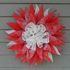 a red and white mesh wreath hanging on the side of a house with a heart