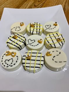 nine decorated cupcakes sitting on top of a white plate with black and yellow icing