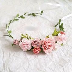 a flower crown with pink flowers and greenery on top of a white tablecloth