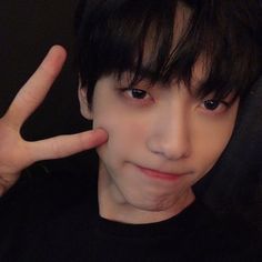 a young man making the peace sign with his hand while wearing a black t - shirt