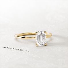 an emerald - cut diamond ring sits on a white surface