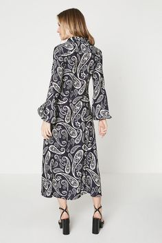 All-over paisley print in monochromatic palette   Midi length with curved hem   Point collar and buttoned cuffs   Soft, woven fabric with fluid drape   Feminine silhouette with slight taper at waist  This effortlessly chic paisley printed midi dress from Oasis is a versatile wardrobe addition. Crafted from a fluid woven fabric, it features an allover monochromatic paisley print that flatters a variety of figures. The midi length shows just the right amount of leg, while the curved hem and point collar add ladylike polish.  Style this dress for work with a blazer and flats or dress it up for weekends with heeled sandals and a crossbody bag. The muted palette allows for creative accessorizing with colourful jewellery, scarves, jackets, and more. Layer it over a turtleneck once the weather Polish Style, Colourful Jewellery, Muted Palette, Dress For Work, Monochromatic Palette, Oasis Dress, Oasis Fashion, Versatile Wardrobe, Feminine Silhouette