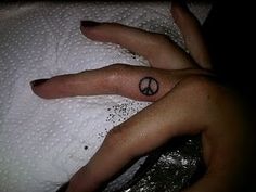 a person's hand with a peace sign tattoo on their left thumb and finger