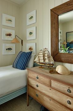 a bed room with a neatly made bed next to a dresser and a mirror on the wall