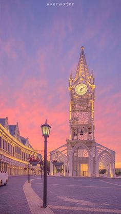 a clock tower in the middle of a town square at sunset with pink and blue sky