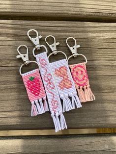 four small key chains with tassels on them sitting on a wooden table next to each other