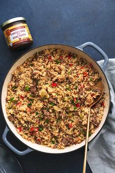 a pot filled with rice and meat next to a spoon