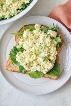 two white plates topped with sandwiches and salad