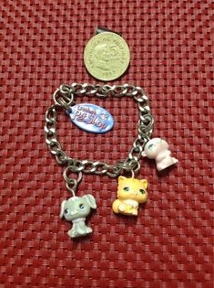 three charms are attached to a chain on a red surface with a penny and an elephant