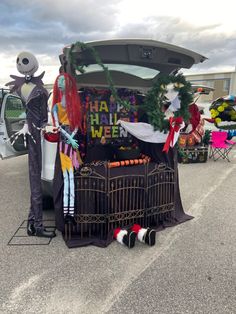 two people dressed up in costumes standing next to an open trunk with decorations on it