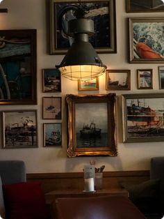 a lamp hanging from the side of a wall filled with pictures