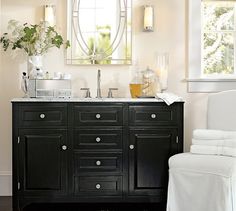 a white chair sitting next to a bathroom sink under a mirror above a counter top