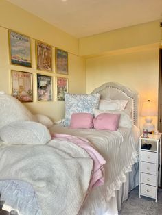 a white bed sitting in a bedroom next to a wall with pictures on the walls