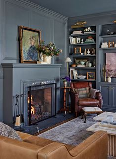 a living room filled with furniture and a fire place in front of a book shelf