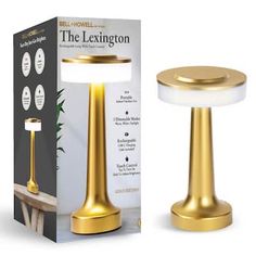 the lamp is gold and has a white light on it's base, next to a cardboard box