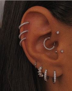 a woman with ear piercings on her left side, and three different pieces of jewelry in the middle