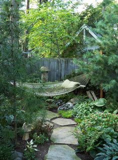 a garden with hammock and trees in the background