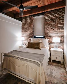 a bed room with a neatly made bed and a ceiling fan above it's headboard