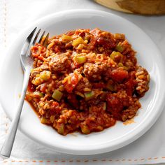 a white plate topped with meat and vegetables next to a bowl of sauce on top of a table