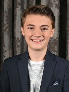 a young man in a suit smiling at the camera