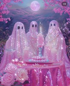 three ghostlyly dressed women sit at a table with pink roses and candles in front of them