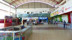 the inside of a shopping mall with people walking around and shops on either side of it