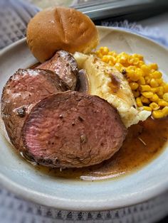 a white plate topped with meat, potatoes and corn