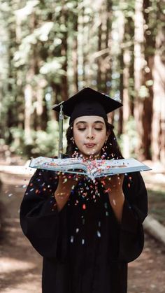 a woman in graduation gown holding a book with confetti coming out of it