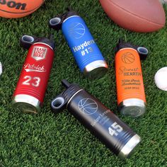 several different sports items are laying on the grass next to each other, including balls and water bottles