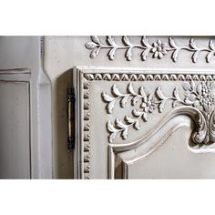 an ornate white painted cabinet door with decorative carvings