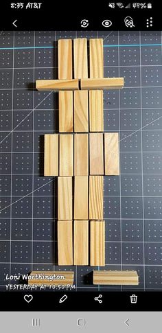 a cross made out of wooden planks sitting on top of a cutting board next to a ruler