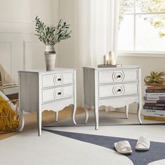 two white nightstands sitting next to each other on top of a carpeted floor