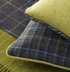 a green and blue plaid pillow sitting on top of a bed next to a blanket