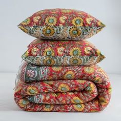 three pillows stacked on top of each other in different colors and patterns, with one pillow folded up to the side