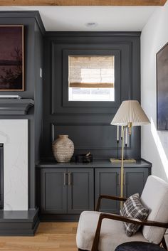 a living room with gray walls and white trim, wood flooring and a fireplace