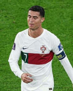 a soccer player in white and red uniform standing on the field with his hands behind his back