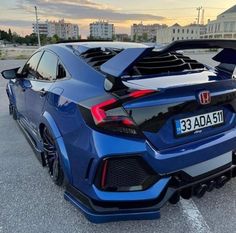 the rear end of a blue car parked in a parking lot