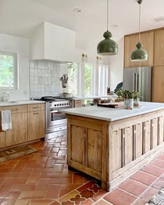 a large kitchen with an island in the middle and two pendant lights hanging from the ceiling