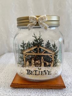 a glass jar with a nativity scene in it on top of a wooden stand