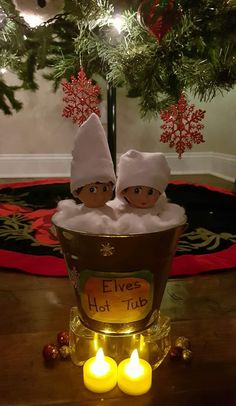 two elfs in a tub with candles on the floor next to a christmas tree