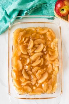 an apple dessert in a glass dish next to apples