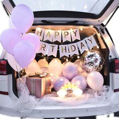 the trunk of a car with balloons and presents in it