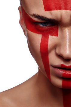 a man with painted on his face is looking at the camera while wearing red and white stripes