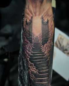 a man with a tattoo on his arm has stairs going up to the sky and clouds